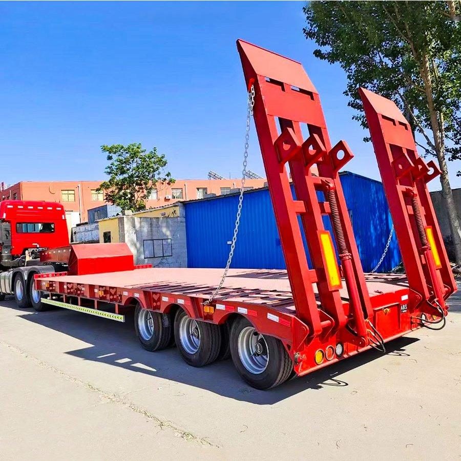 Red three-axle lowbed semi-trailer with loading ramps raised